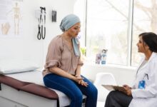 A-breast-cancer-patient-sits-on-the-examination-table-and-shares-her-symptoms-with-her-physician_GettyImages-2148188847-1536x1024